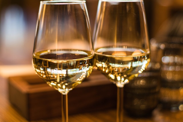 Deux verres de vins blancs avec une robe très claire sont posées sur un table côte à côte